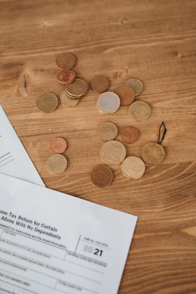 Coins scattered on a wooden surface alongside tax documents, evoking financial themes.